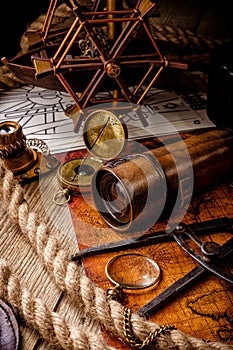 Old vintage retro compass and spyglass on ancient world map