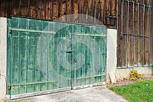 Old vintage rustic green wooden barn door on a wooden shed