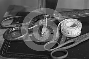 Old vintage sewing machine with an old rusty pair of scissors and a Tape Measure Sewing Tailor Cloth Ruler.