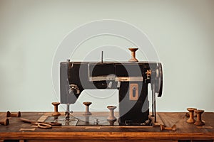 Old vintage sewing machine on wooden table on white wall background
