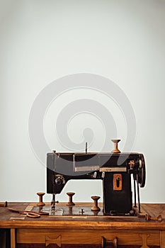 Old vintage sewing machine on wooden table on white wall background