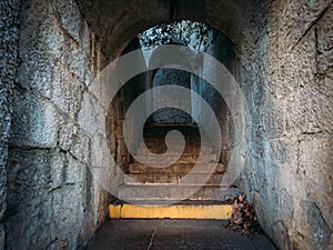 Old vintage steps of stone staircase in narrow corridor of ancient building