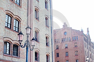 Old vintage street lamp covered with patina on the background of red, orange brick buildings