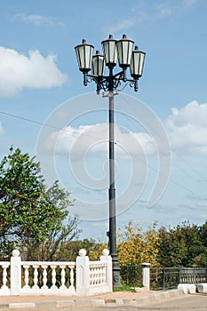 Old vintage street lamp post or lantern with light bulbs against a sky background