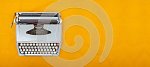 Old vintage style typewriter top view photo on yellow background