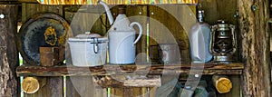 Old vintage tableware on a wooden shelf, some rusty old cups and plates, historical and primitive equipment