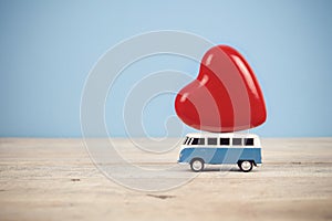 Old vintage toy van with big red heart figure on top in blue background