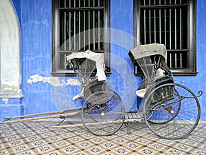 Old vintage traditional rickshaws in front of blue building in P