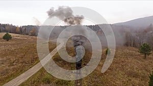 Old vintage train locomotive moving through the breathtaking forest railway, mountains landscape, autumn colors, drone shot