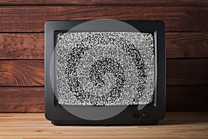 Old vintage TV set televisor on wooden table againt dark wooden wall background with no signal television grainy noise effect on