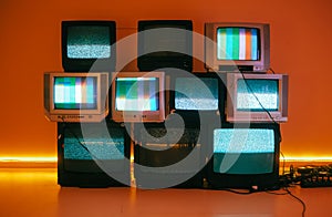 Old vintage tvs on a floor in a room with colored neon light photo