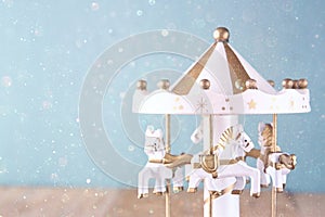 Old vintage white carousel horses on wooden table. retro filtered image with glitter overlay