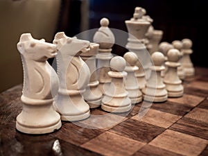 Old vintage white chess on wooden chessboard