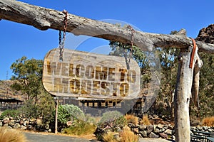 old wood signboard with text welcome to Modesto. hanging on a branch photo