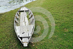 A old vintage wooden boat on the green grass beside a pond in the park, vinatge classic stlye