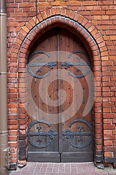 Old vintage wooden gothic door on a medieval building facade