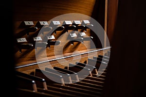 Old Vintage Wooden Pipe Organ Foot Pedal Keyboard Close Up Contrast with Shadows and Notes.