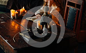 On the old vintage wooden table is a candlestick with candles. A red-haired girl in vintage clothes is sitting at the table, readi