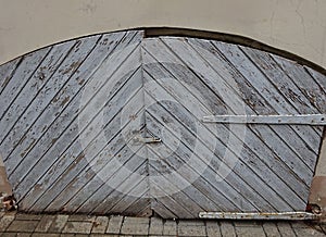 Old vintage wooden weathered arch entrance doors with rust metal details and paint crackle effect