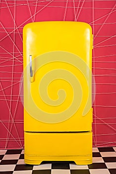 Old vintage yellow refrigerator on a pink background