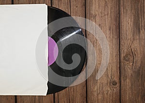 Old vinyl record in paper case on wooden rustic background