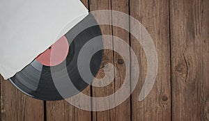 Old vinyl record in paper case on wooden rustic background.