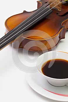 Old violin and cup of coffee on the white table