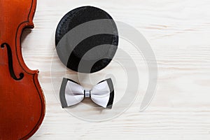 Old violin, cylinder hat and  bow tie on the white wooden background. Top view, close-up