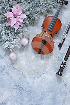 Old violin and flute with fir-tree branches with gentle pink poinsettia flower and Christmas decor. Christmas and New Year`s