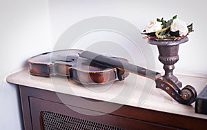 Old violin near a flower vase with roses