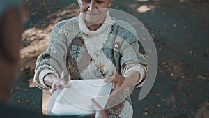 Old vulnerable homeless woman getting free charity meal