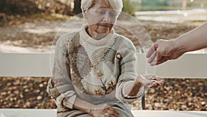Old vulnerable lost or homeless woman getting coins. Dementia and mental issues concept