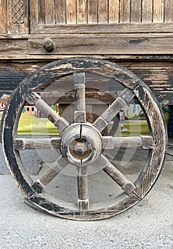 Old wagon wheel side by wooden wall