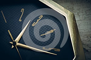 An old wall clock lies on a window sill with peeling paint, the clock hands are made of yellow metal and the dial is black