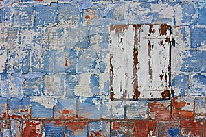Old wall with peeling paint and closed white window