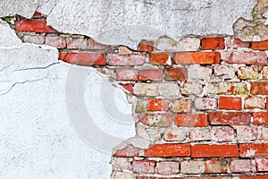 Old wall of red brick with loose plaster.