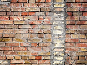 On an old wall of red bricks a separated vertical fragment of the old silicate brick