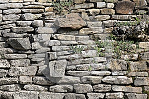 The old wall of stones overgrown with grass and moss