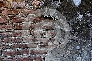 The old wall, which has a layer of cement peeled off, shows the bricks.