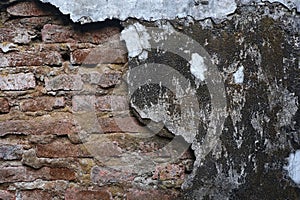 The old wall, which has a layer of cement peeled off, shows the bricks.