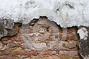 The old wall, which has a layer of cement peeled off, shows the bricks.