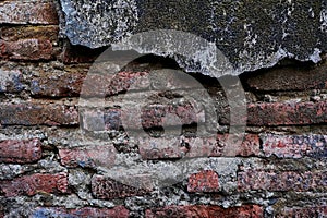 The old wall, which has a layer of cement peeled off, shows the bricks.