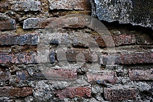 The old wall, which has a layer of cement peeled off, shows the bricks.