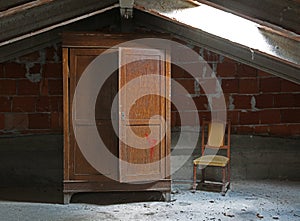 Old wardrobe and a chair in the uninhabited attic