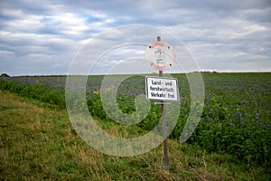 Old washed-up prohibition sign on a field on a dirt road. No car or motorcycle landmaschiene free. Germany