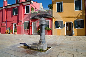 Old water distributing column in the sunny day. Burano Island, Venice