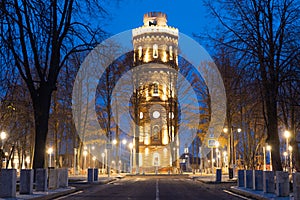 An old water tower against the backdrop of an illuminated evening street at Zaraysk, Russia