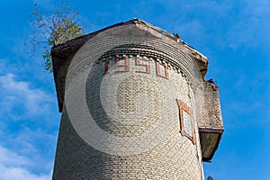 Old water tower built in 1950 with a tree on the roof on the territory of the military town of Balabanovo-1