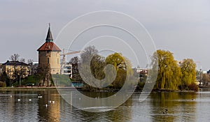 The old water tower and the lake in front of it in the park Pildammsparken in MalmÃ¶, Sweden, on a cold spring day