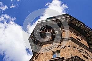 Old water tower made of ancient bricks on a background of blue sky with clouds